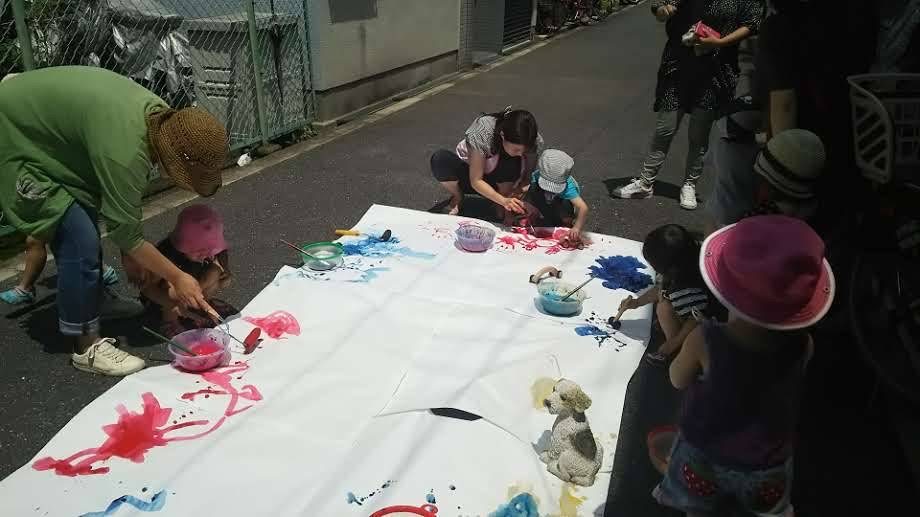 大きな紙に、親子で絵の具をのせて遊んでいるところ