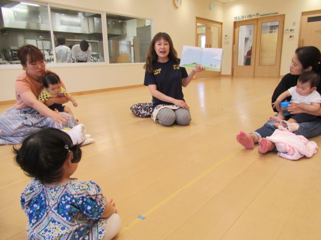 絵本の読み聞かせをする主宰と、聞いている親子